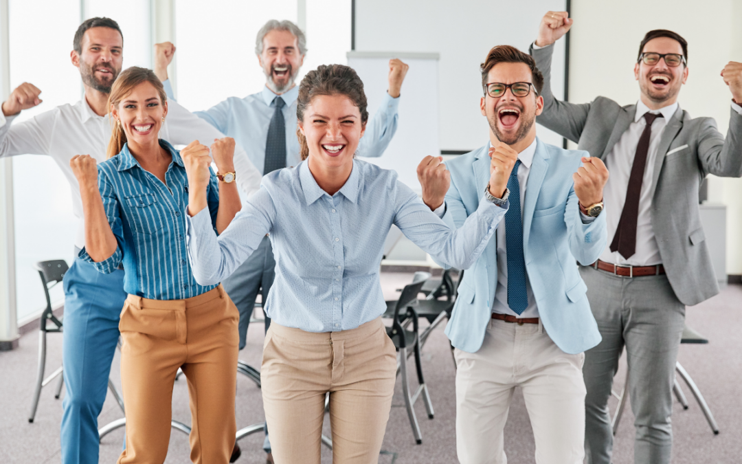 A diverse team of professionals celebrating together with raised fists in a modern office environment